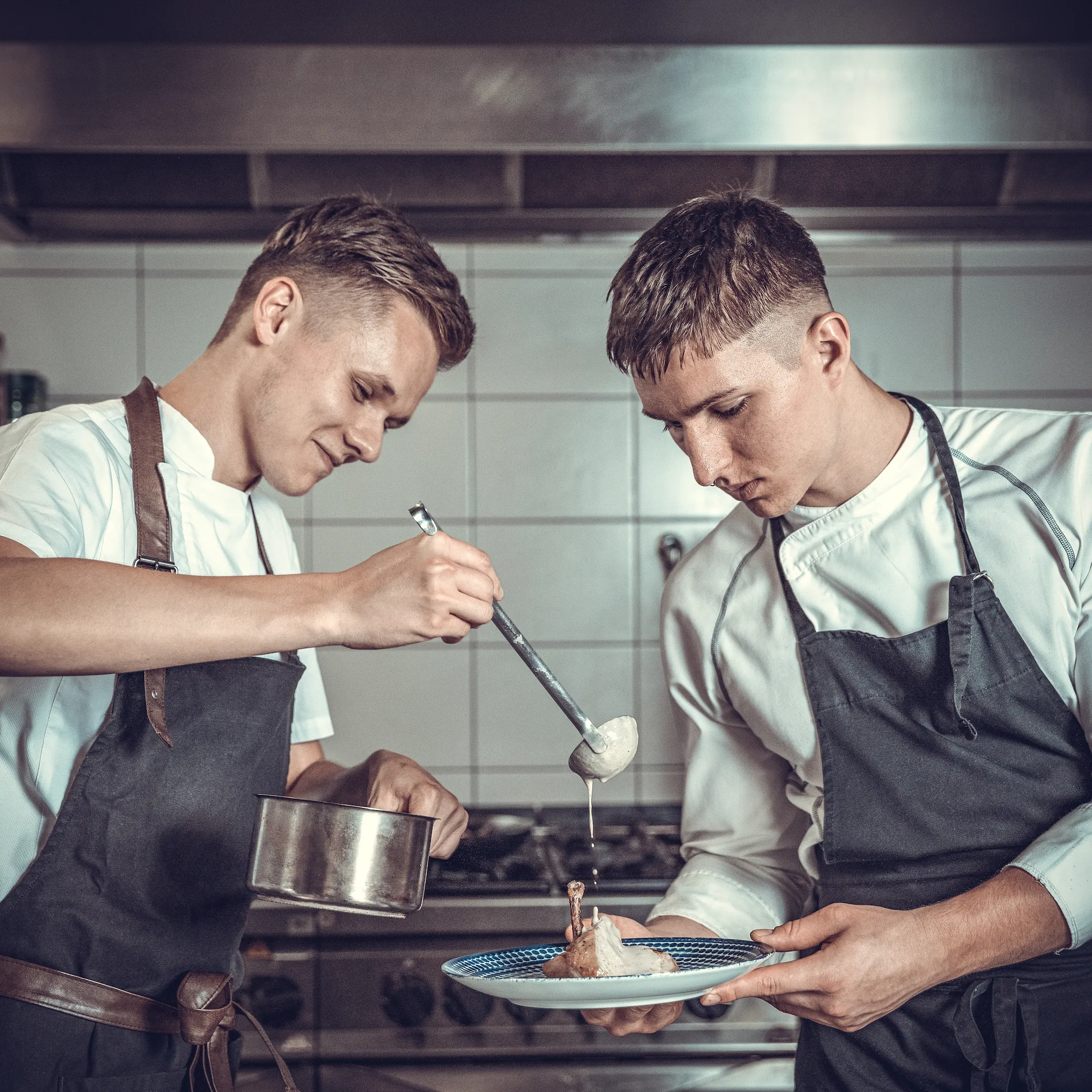 Angebot 69 preparing meat with sauce by two young chefs