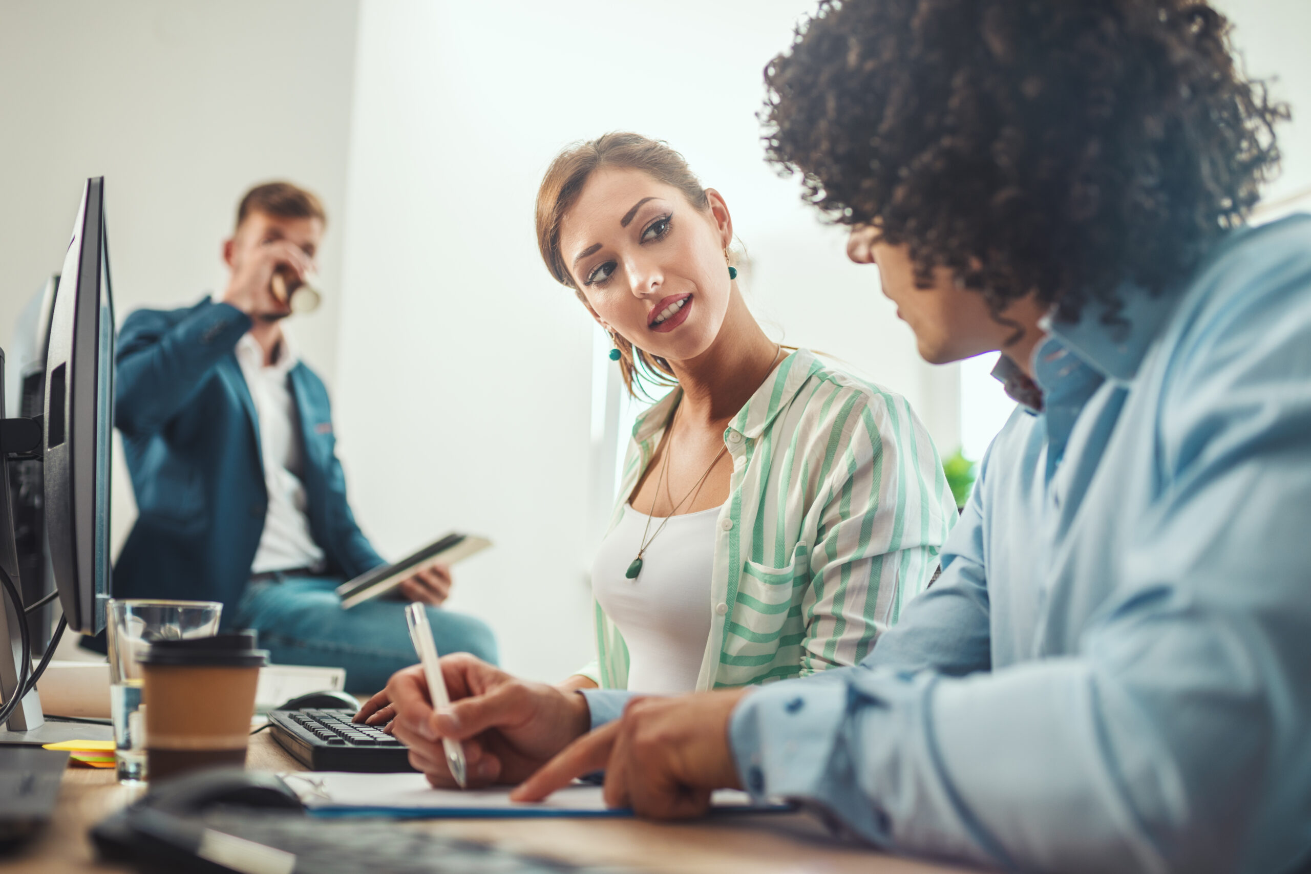 Angebot 23 young business people are discussing about some documents while working desktop computer casual office scaled