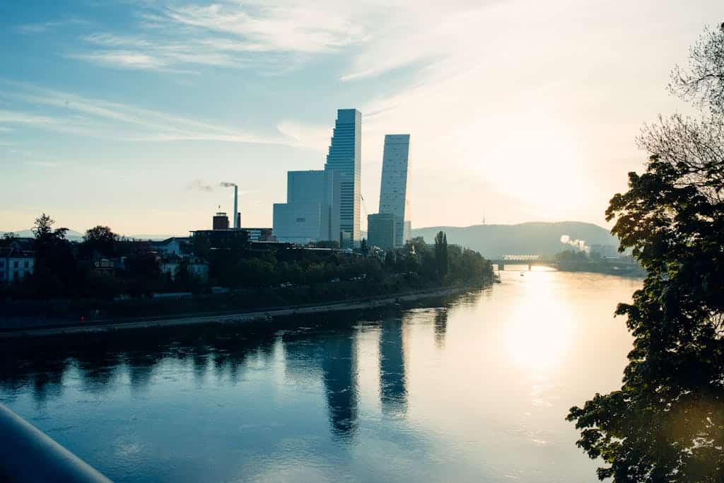 Captivating Basel skyline with modern architecture reflected in the Rhine at sunset.